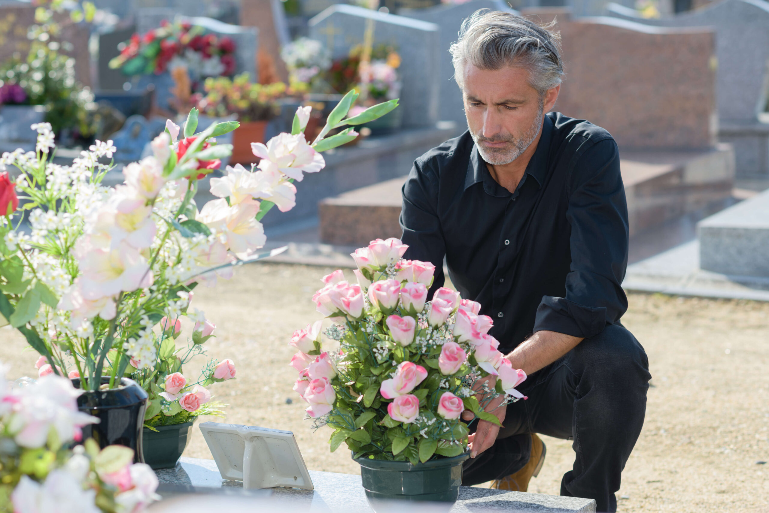 Стал вдовцом. Человек несет цветы на могилу. Цветы на кладбище мужчине. Мужчина кладет цветы на могилу. Вдовец у могилы.