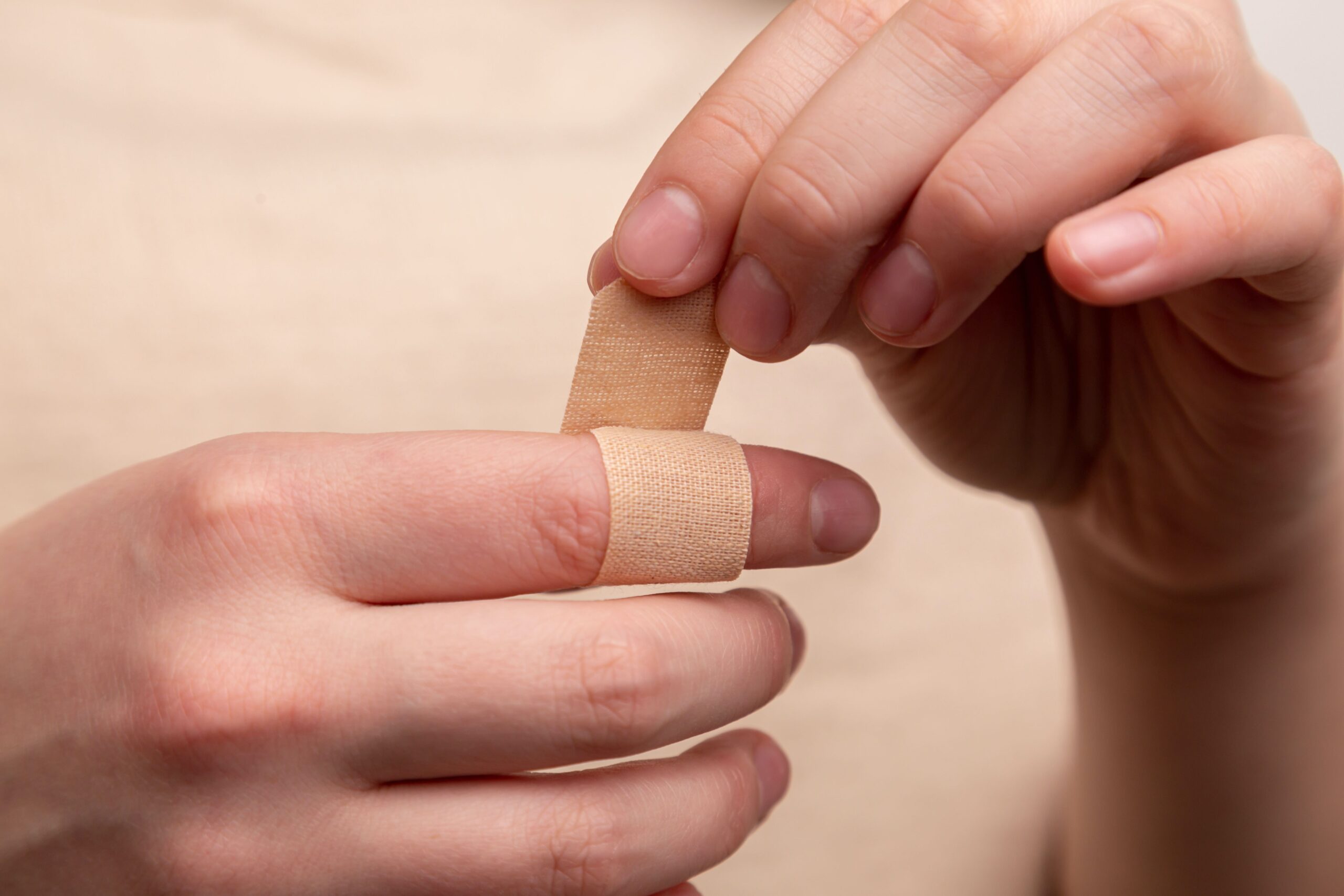 A person putting a bandaid on their finger.